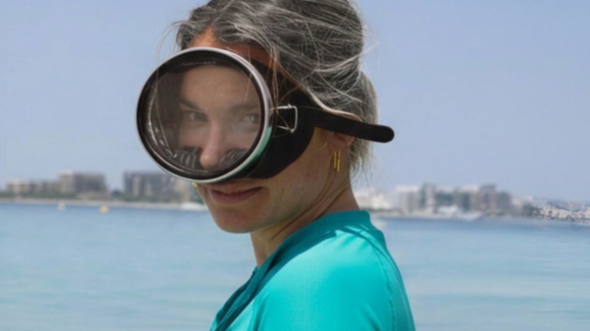 woman in a green rash top with snorkelling goggles on