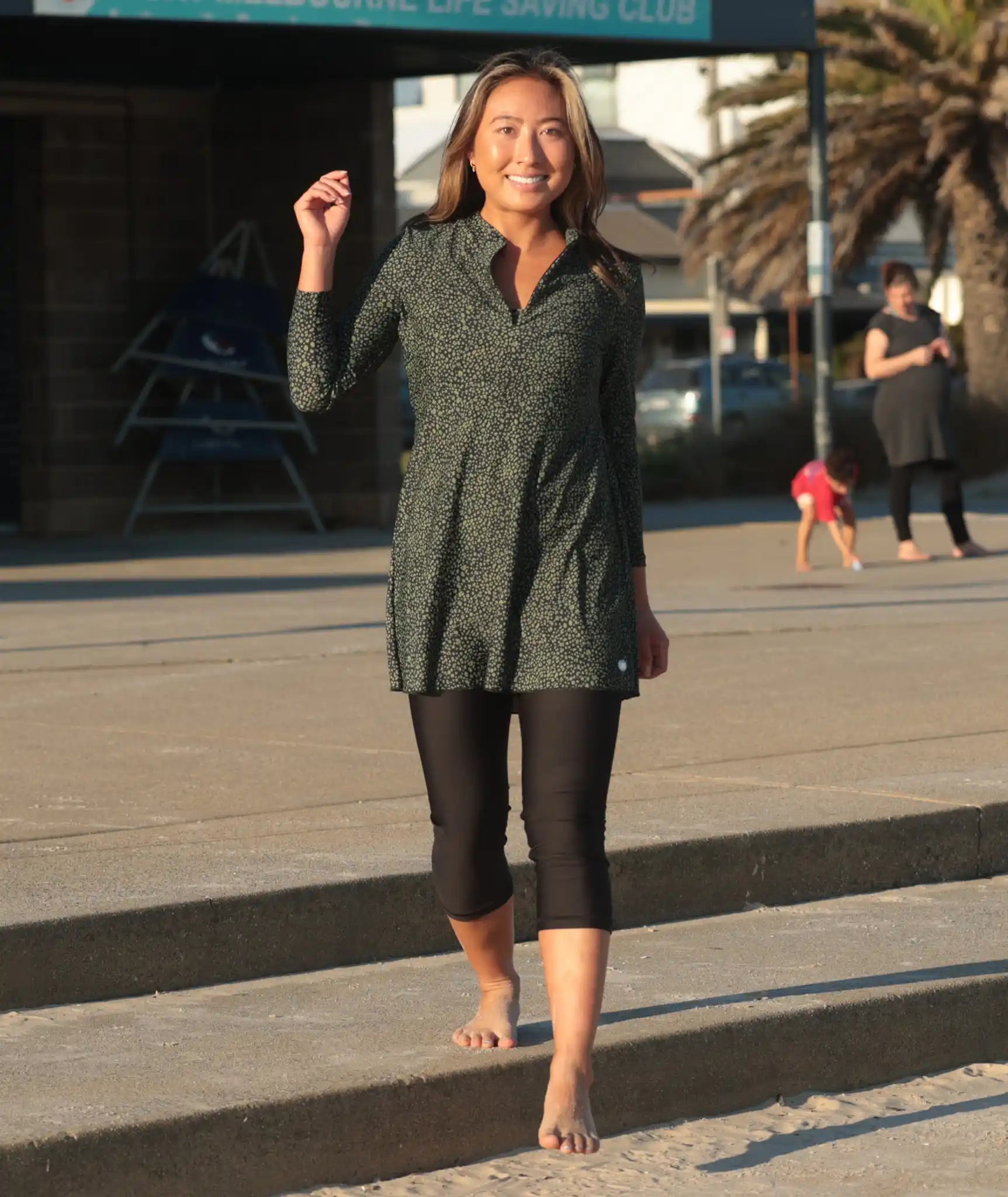 Woman wearing a green spot print long sleeve swim dress with black swim leggings, UPF50+ full coverage swimwear