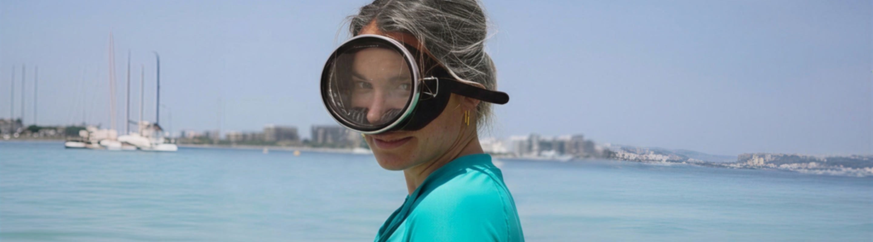 woman in a green rash top with snorkelling goggles on