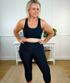 Swim woman in black cropped swim leggings and a swim crop top standing in a room