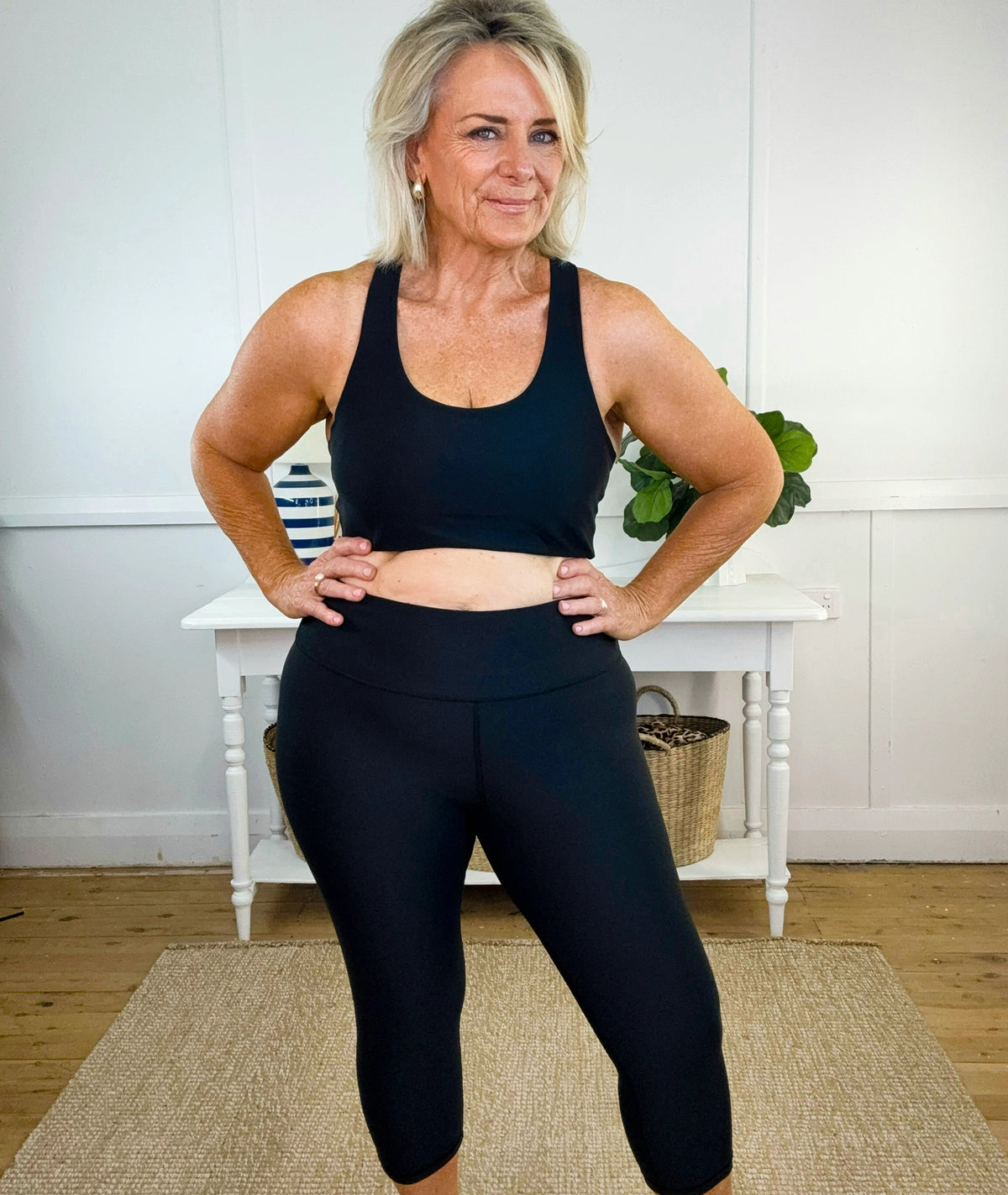 Swim woman in black cropped swim leggings and a swim crop top standing in a room