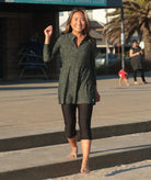 Woman wearing a green spot print long sleeve swim dress with black swim leggings, UPF50+ full coverage swimwear